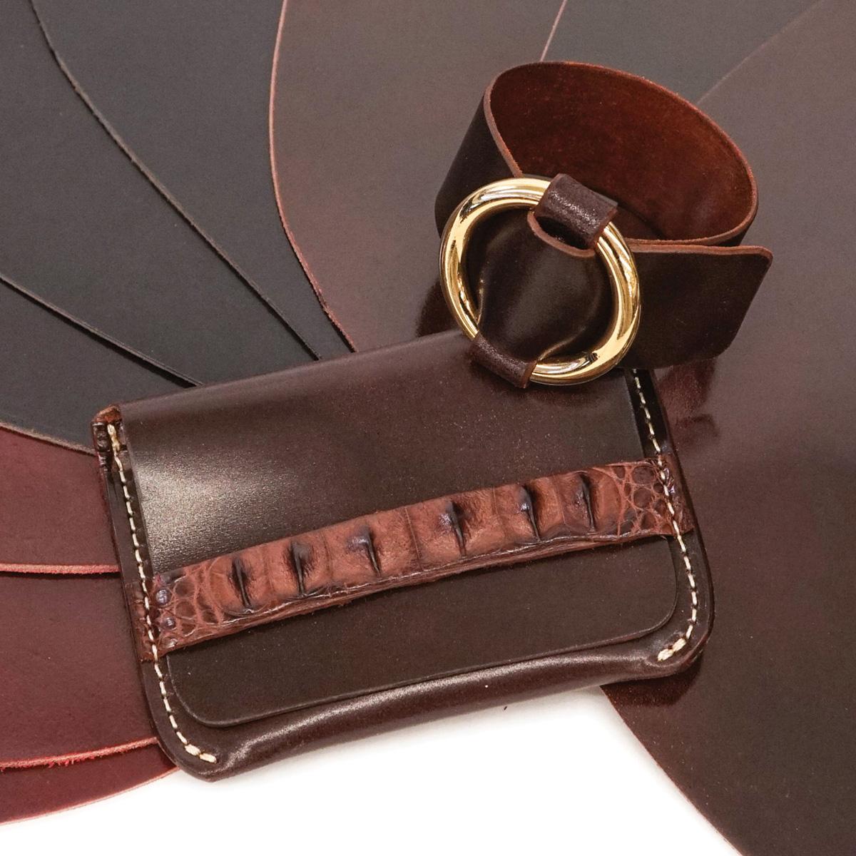 a shell cordovan wallet and cuff sit on top of several shell codorvan pieces in three colors